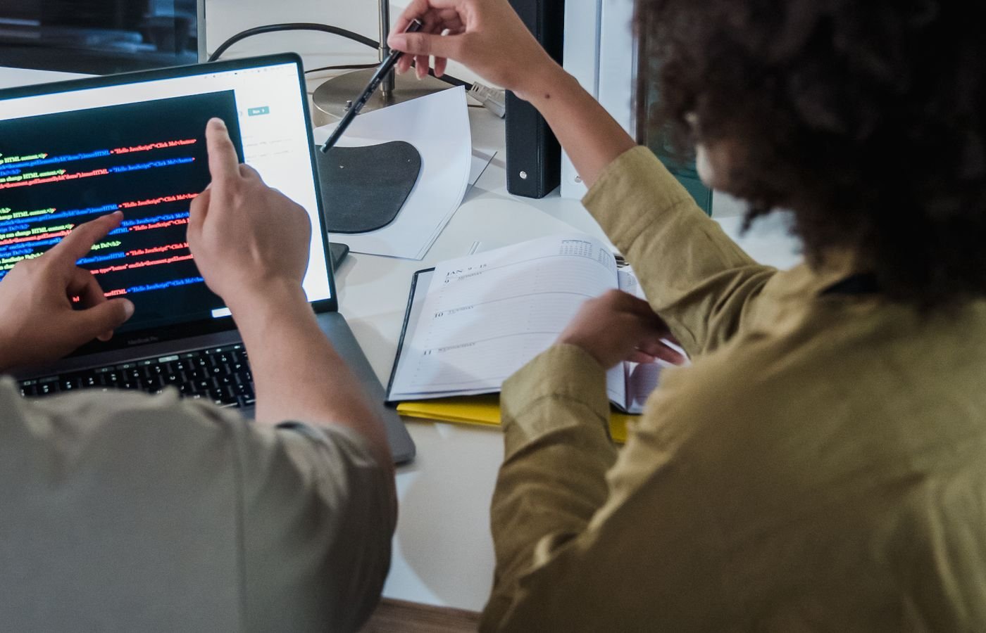 Two developers reviewing code together on a laptop