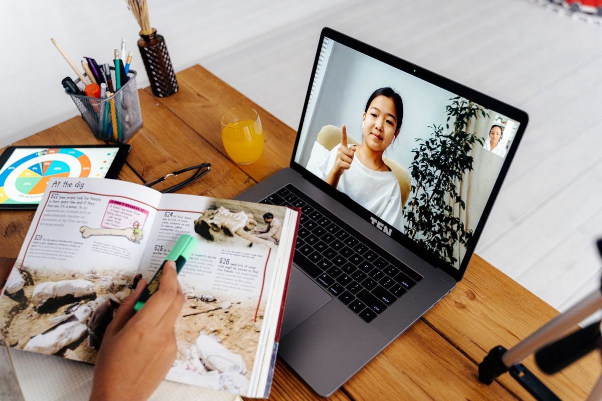 Learner on a video call beside an open notebook